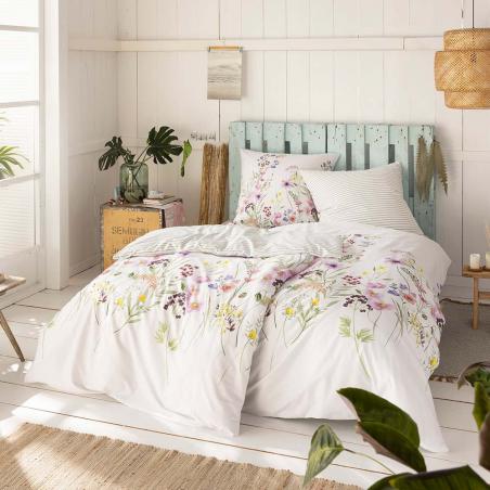 Pościel Estella Rosie w polne kwiaty w odcieniach różu, żółtego, zieleni na białym tle na łóżku w sypialni.